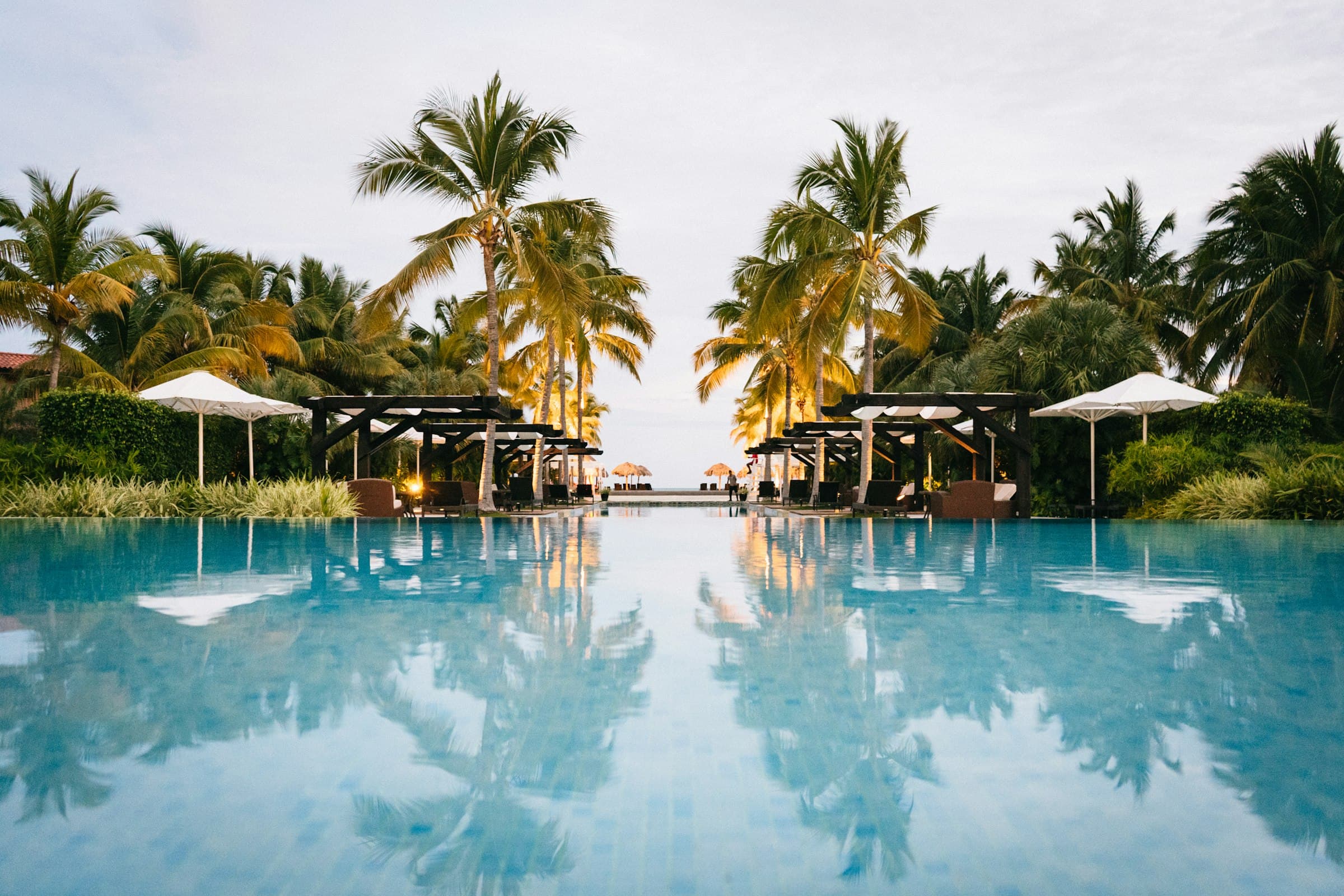 5-star luxury hotel outdoor pool terrace with palm trees and sun umbrellas